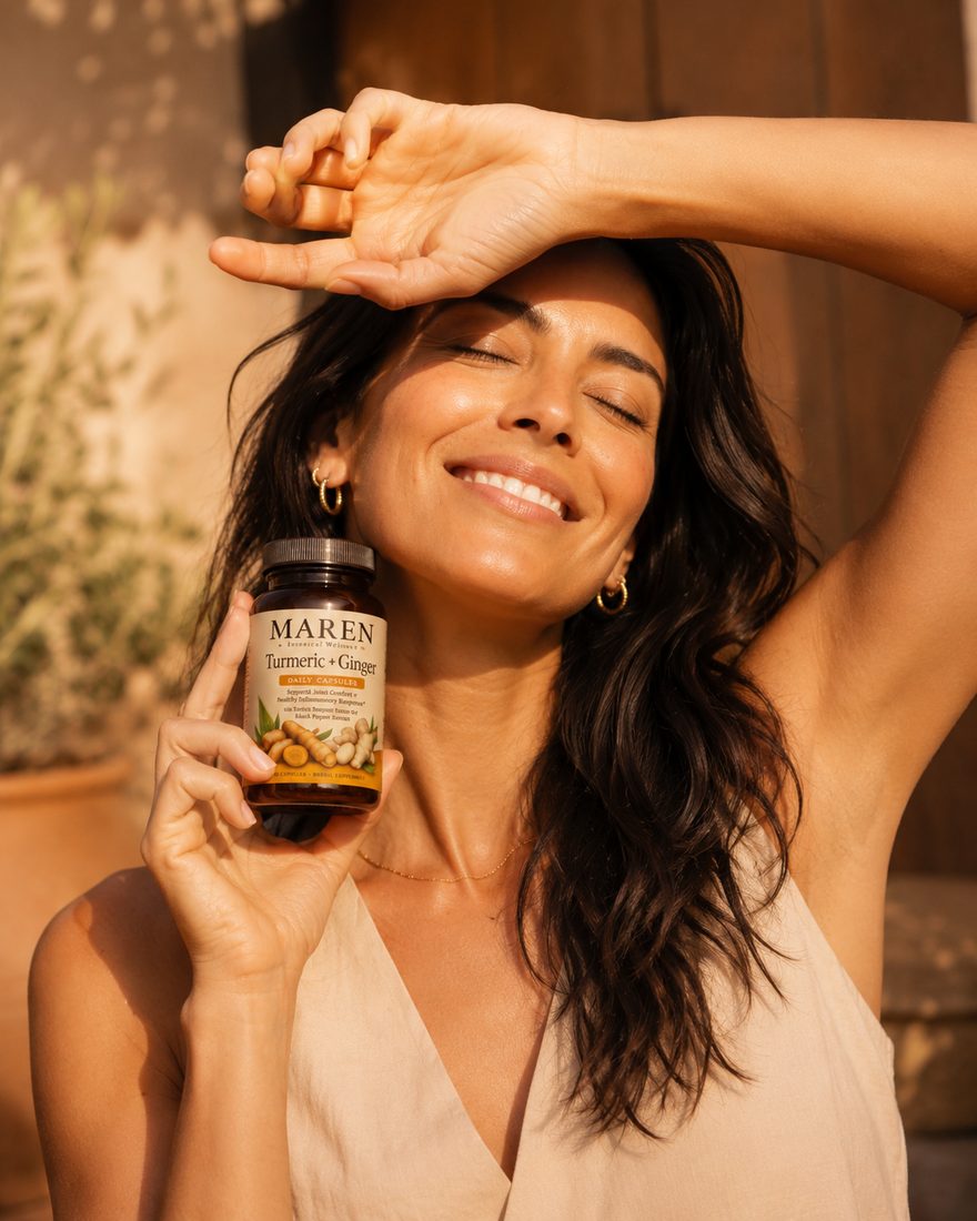 Woman with arm raised in golden hour light holding the MAREN bottle near her face